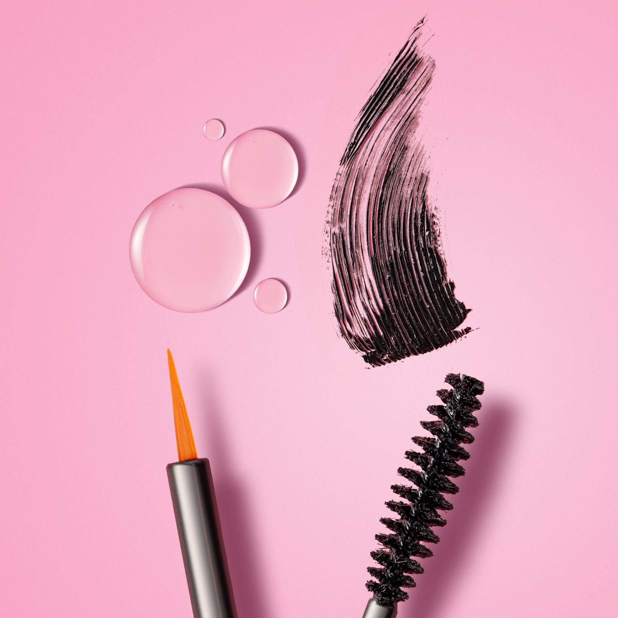 Close-up of Lash Therapy Australia growth serum mascara wand with mascara formula swatch on pink background.